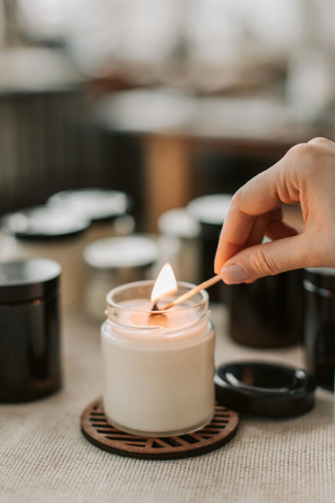 pexels-photo-6755860-6755860 Close-up of a hand lighting a handmade candle with a matchstick, creating a cozy ambiance.